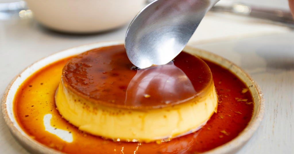 カラメルが広がるプリンの表面とスプーンの様子