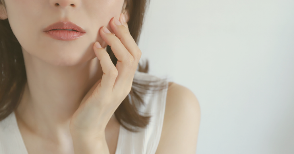 頬に違和感があり肌に触れる女性のイメージ